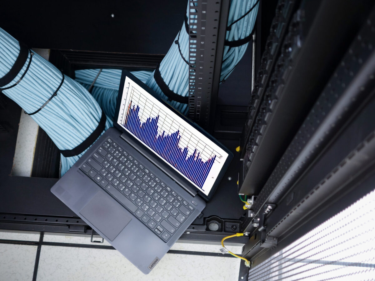 Data Analysis in Server Room with Laptop Displaying Graph